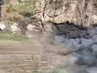 2 RU soldiers by a camouflaged tank are hit by artillery