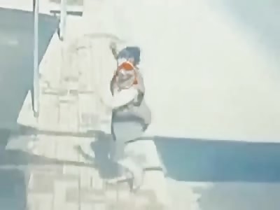 Woman throwing water in the street nearly hit by speeding car.